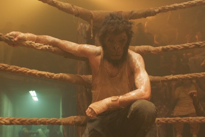 A man in a monkey mask (Dev Patel) rests in the corner of a boxing ring in Monkey Man (2024).