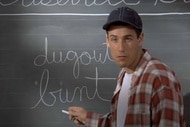 Billy Madison (Adam Sandler) writes on a chalkboard in Billy Madison (1995).