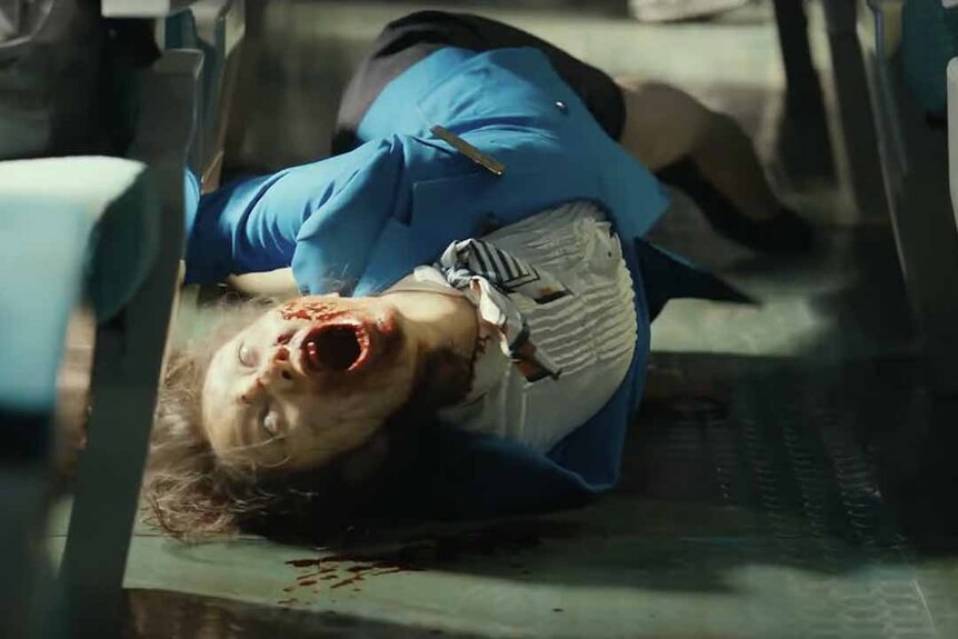 A zombie train attendant writhes on the floor in Train to Busan (2016).
