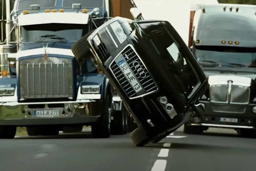 A car drives sideways between two trucks in Transporter 3 (2008).