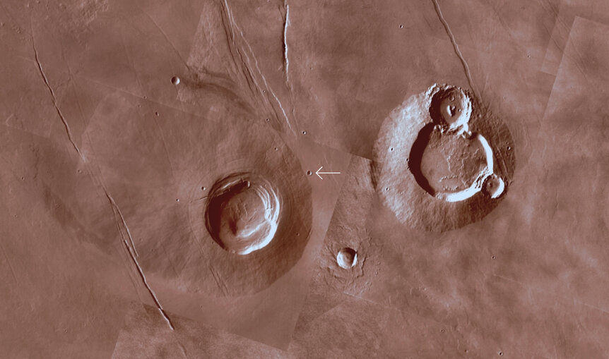 The area around a Martian crater for context shows two large volcanoes nearby (the famous and much larger Tharsis volcanoes are off to the lower right). The image is about 420 km across. Credit: Mars Trek/NASA/JPL-Caltech