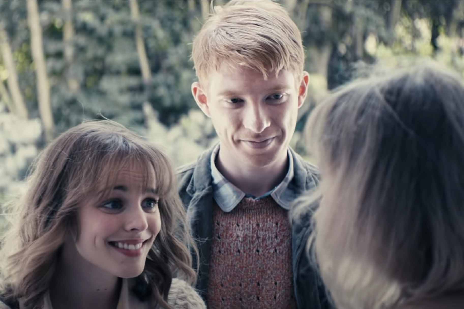 Mary (Rachel McAdams) and Tim Lake (Domhnall Gleeson) smile at a woman in About Time (2013).