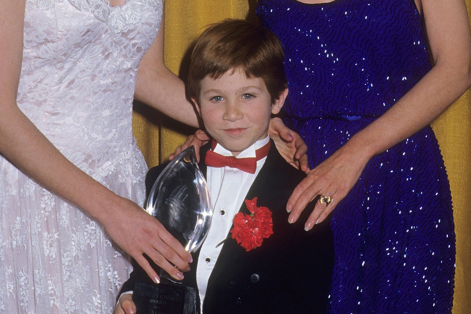 Benji Gregory smiles next to a people's choice award.