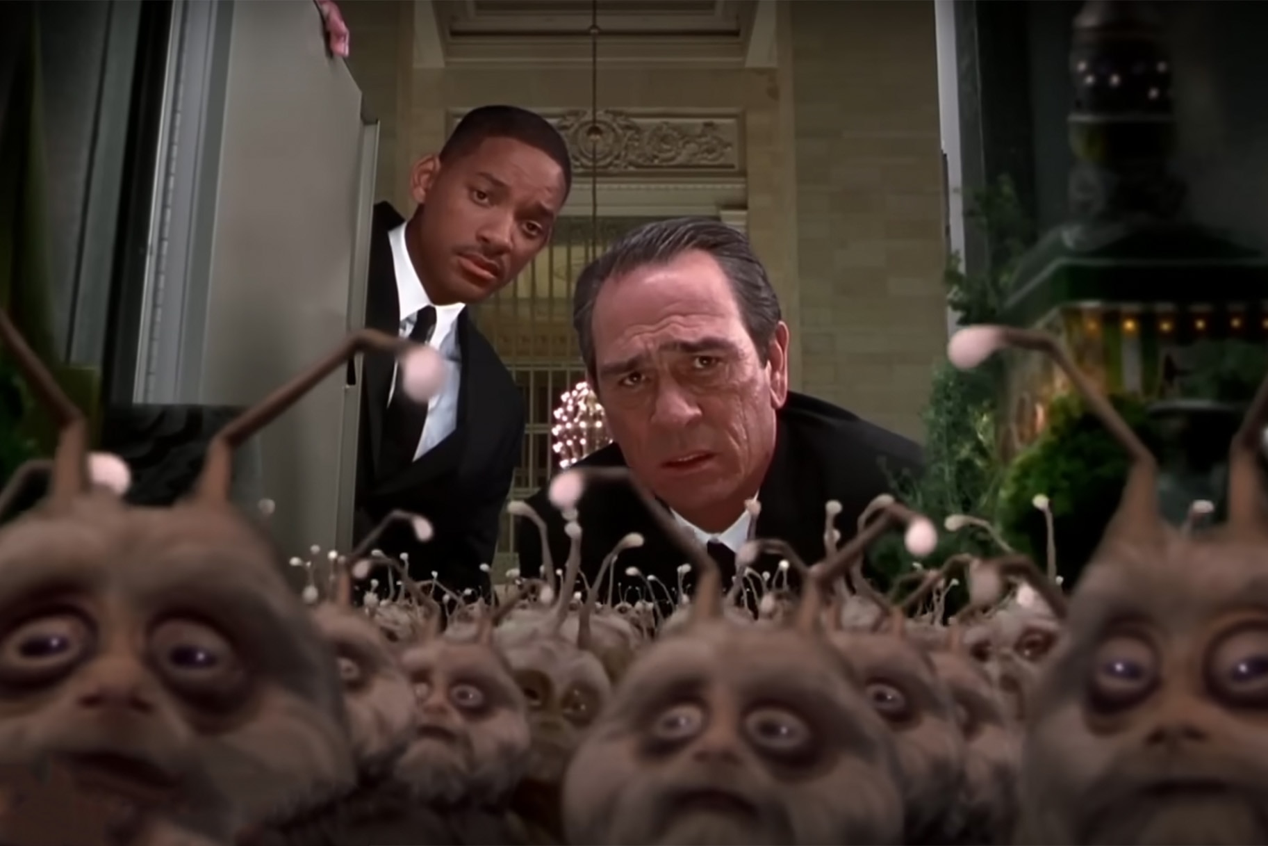 Agents K (Tommy Lee Jones) and J (Will Smith) look at a crowd of aliens in a locker in Men in Black II (2002).