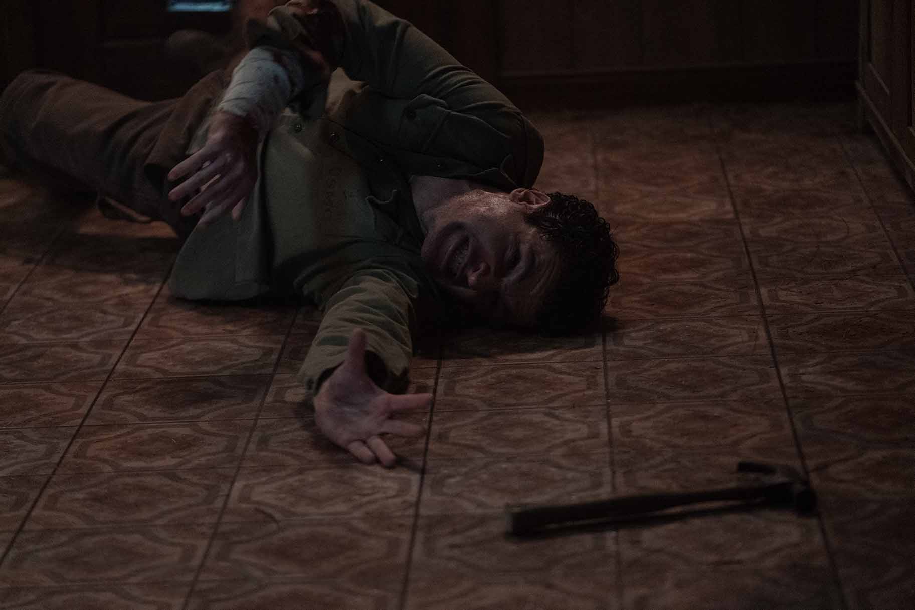 Blake (Christopher Abbott) writhes on the ground and reaches for a hammer in Wolf Man (2024).