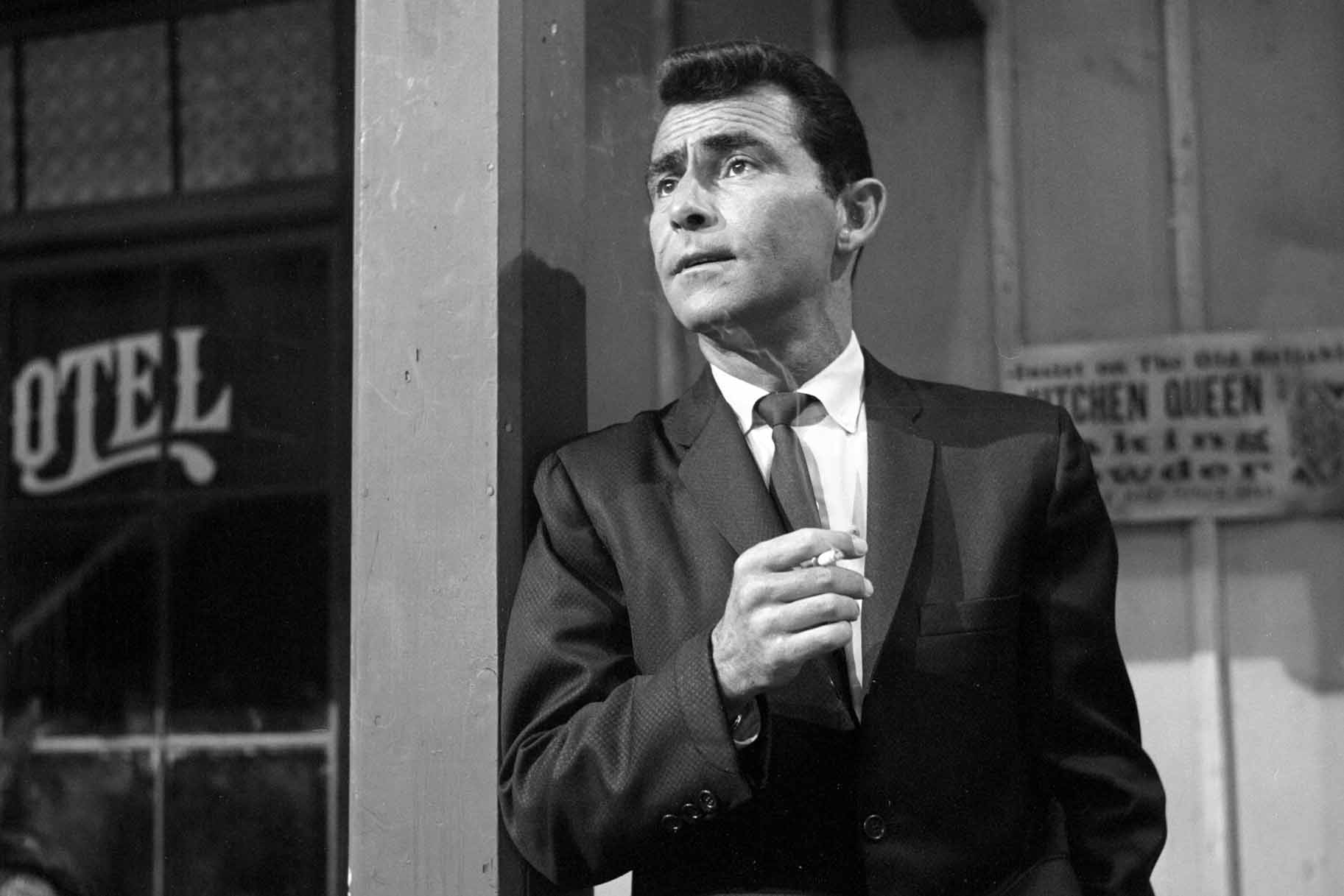 Rod Serling leans against a post with a cigarette.