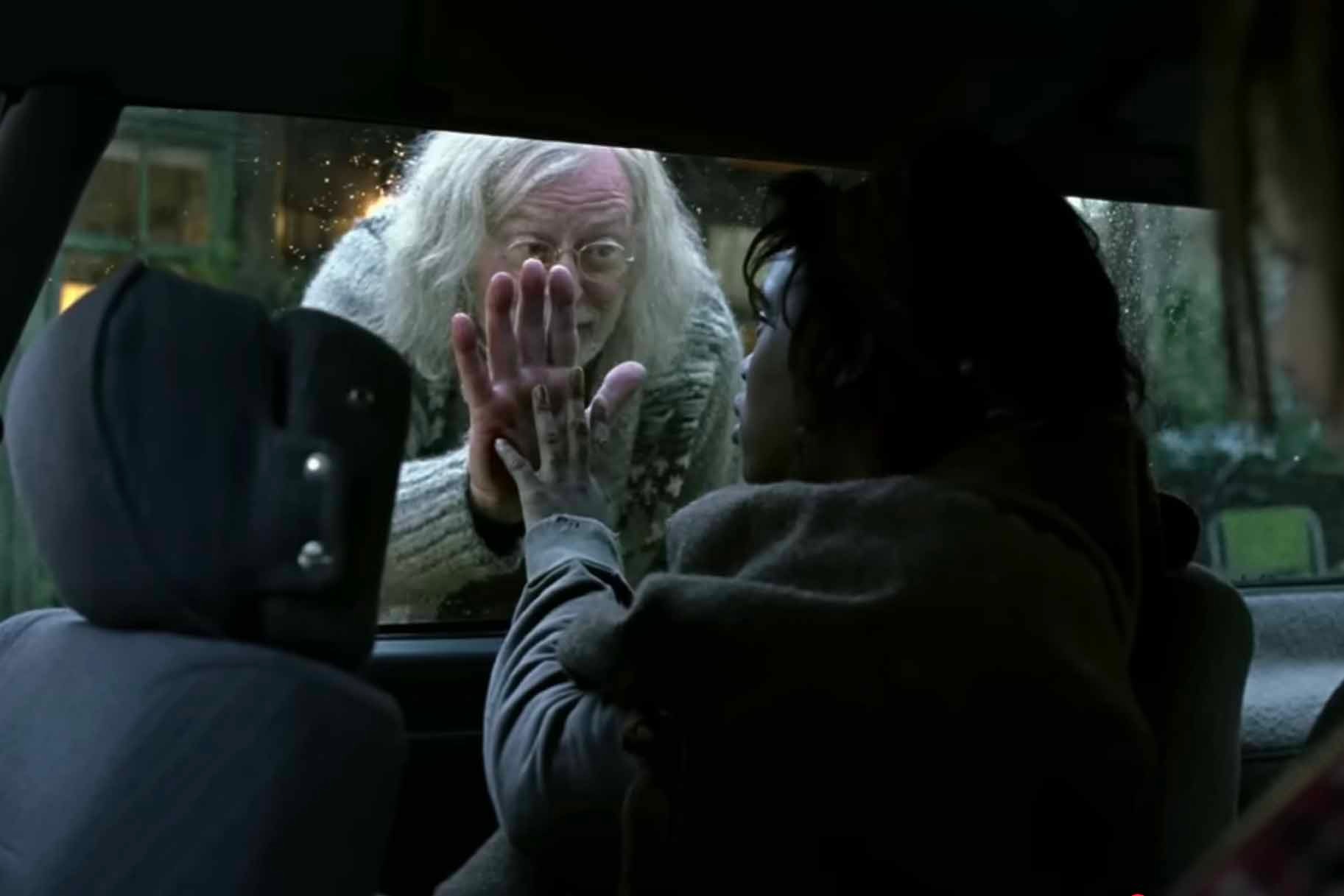 Jasper Palmer (Michael Caine) and Kee (Clare-Hope Ashitey) touch hands across a car window in Children of Men (2006)