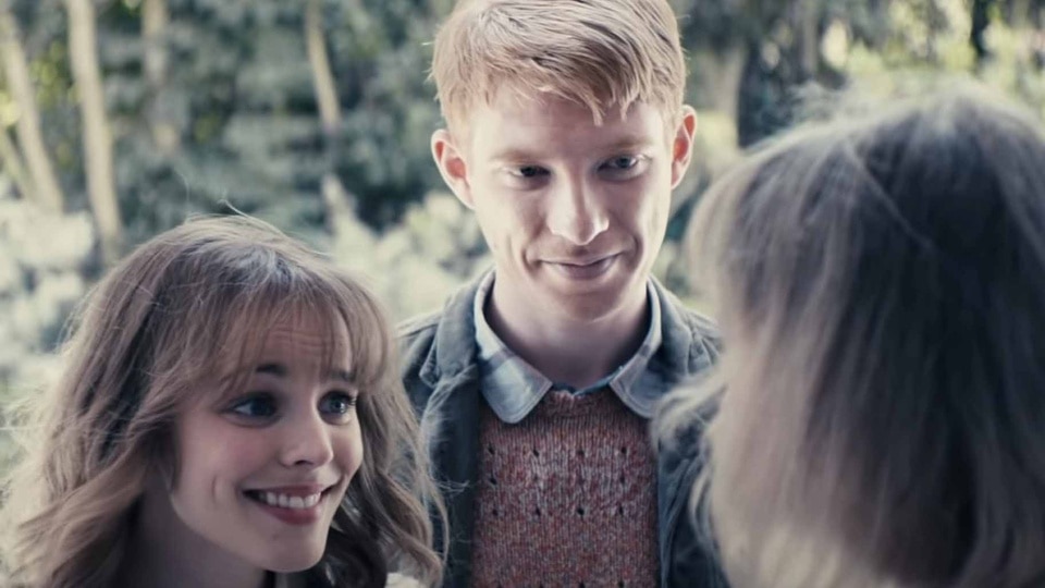 Mary (Rachel McAdams) and Tim Lake (Domhnall Gleeson) smile at a woman in About Time (2013).