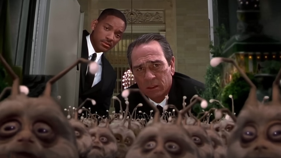 Agents K (Tommy Lee Jones) and J (Will Smith) look at a crowd of aliens in a locker in Men in Black II (2002).