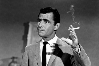 Rod Serling holds a lit cigarette.