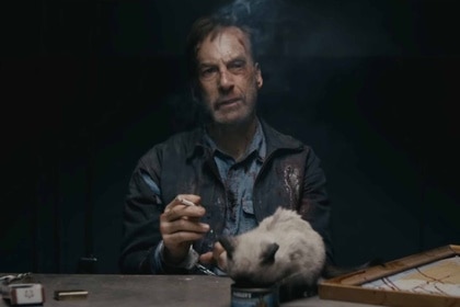 Hutch Mansell (Bob Odenkirk) smokes a cigarette at an interrogation table with a cat in Nobody (2021).