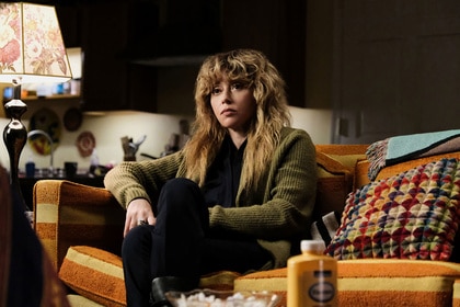 Charlie Cale (Natasha Lyonne) sitting on a sofa in Poker Face Season 1, Episode 5.