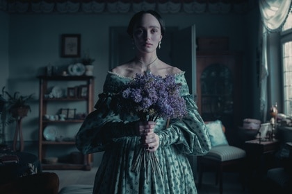 Ellen Hutter (Lily-Rose Depp) holds a bouquet of purple flowers in Nosferatu (2024).