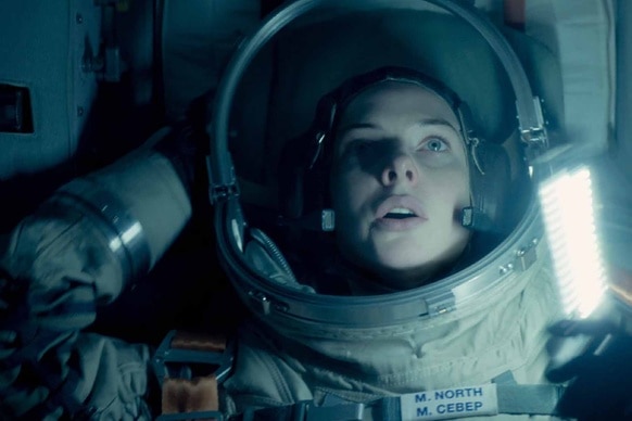 Miranda North (Rebecca Ferguson) holds a flashlight in a space suit in Life (2017).