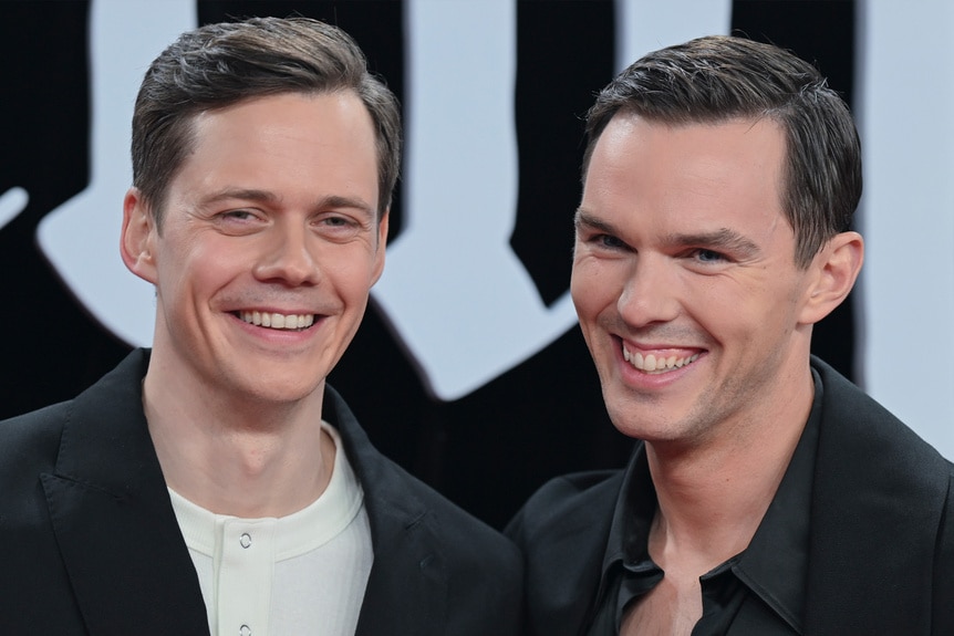 Bill Skarsgard and Nicholas Hoult laugh together.