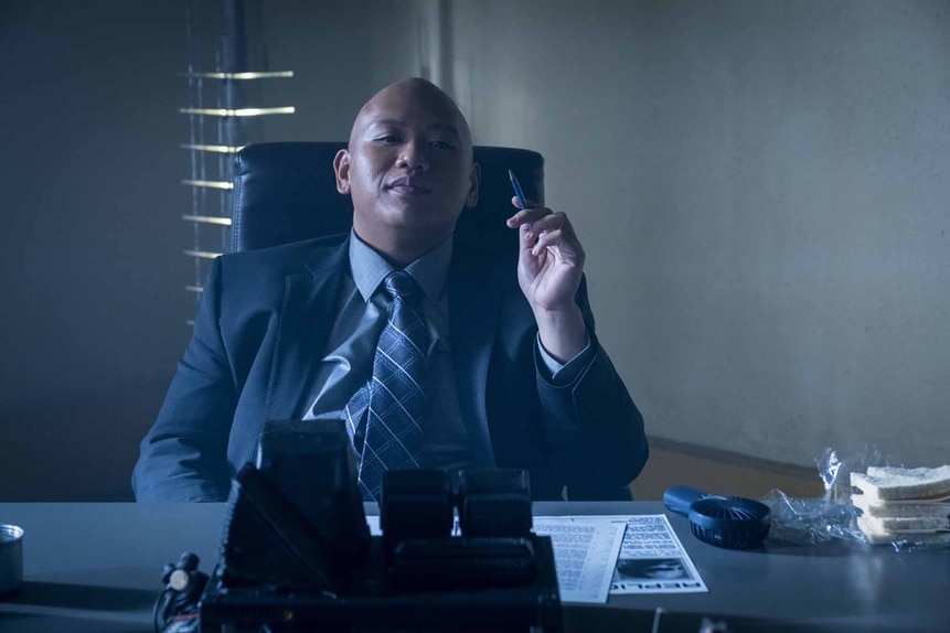 Reginald Andres sits at a desk in a suit in Reginald The Vampire Episode 203.