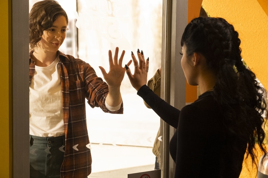 Ashley Weeks (Marguerite Hanna) and Nikki (Christin Park) hold their hands on either side of a window on Reginald the Vampire Episode 208