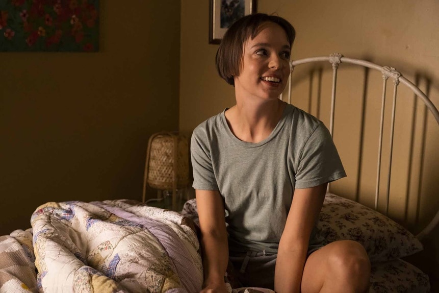 Sarah Kinney (Em Haine) smiles while sitting on a bed on Reginald the Vampire Episode 210.