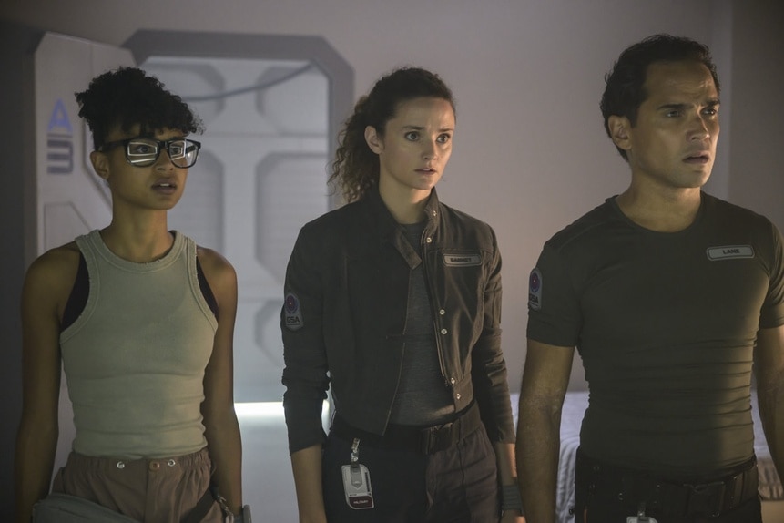 Alicia Nevins (Stacey Read), Lt. Sharon Garnet (Christie Burke), and Lt. Spencer Lane (Reece Ritchie) walk through dim light on The Ark Episode 204.