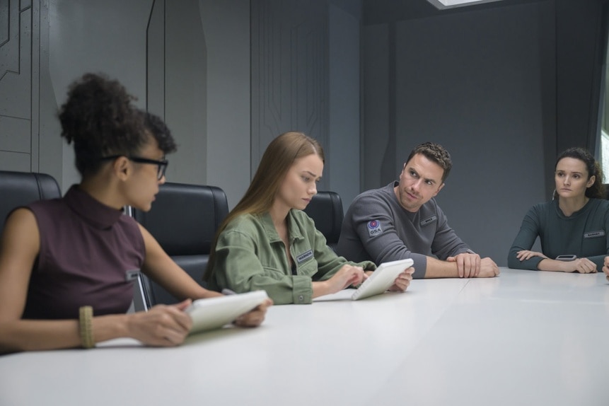 The cast sits at a table and reads on The Ark Season Episode 207.