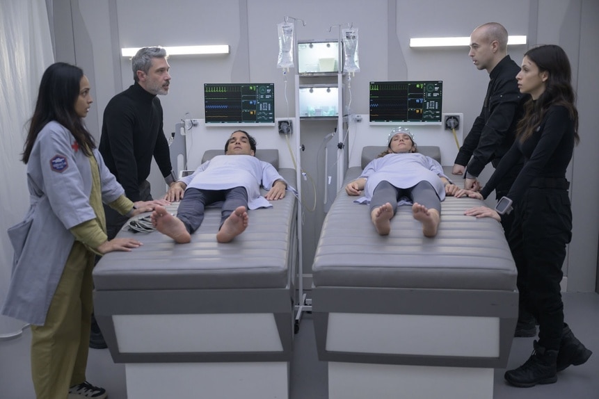 Doctors surround Ian (Reece Ritchie) and Lt. Sharon Garnet (Christie Burke) who lay on hospital beds in The Ark Episode 210.