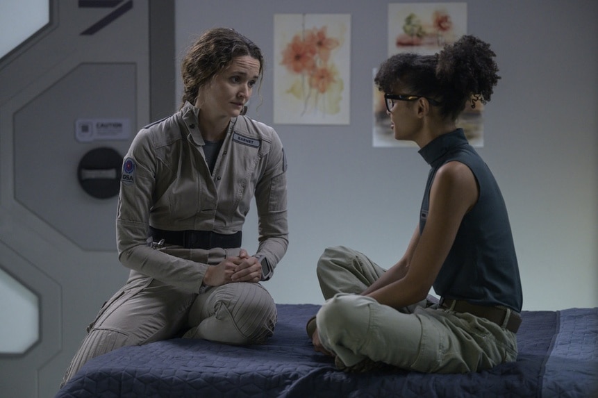 Lt. Sharon Garnet (Christie Burke) and Alicia Nevins (Stacey Read) speak together on a bed on The Ark Episode 211.