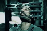 Cecil Adams (Billy Otis) is trapped in a chair with knives pointed at his face in Saw IV (2007)