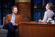 Glen Powell smiles at Seth Meyers during an interview