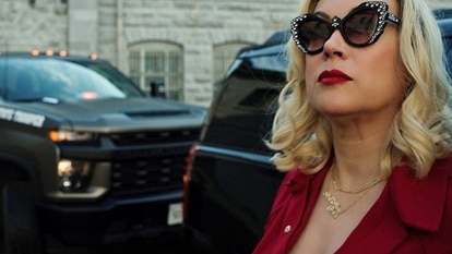 Tiffany (Jennifer Tilly) wears sunglasses and stands in front of trucks in Chucky 304.