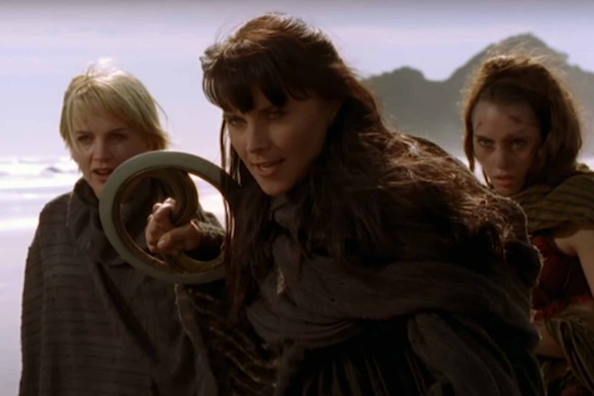 Xena (Lucy Lawless) holds a weapon and has two women behind her in Xena: Warrior Princess Episode 522.