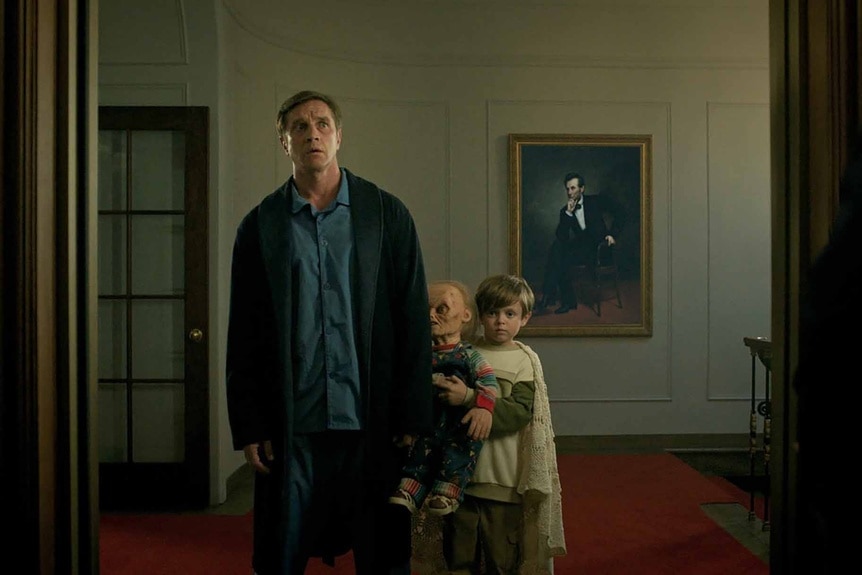 President James Collins (Devon Sawa), Chucky, and Henry Collins (Callum Vinson) walk through a hallway in Chucky Episode 306.