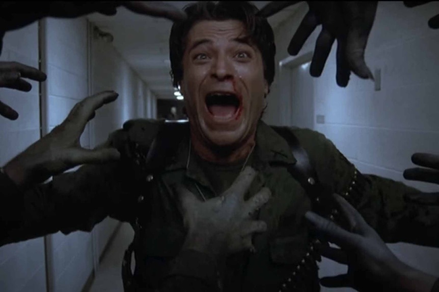 Captain Henry Rhodes (Joseph Pilato) screams as zombie hands reach out toward him in Day of the Dead (1985).