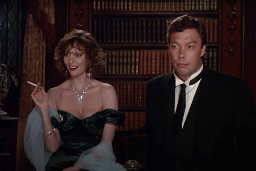 Miss Scarlet (Leslie Ann Warren) and Wadsworth (Tim Curry) stand in formalwear in Clue (1985).