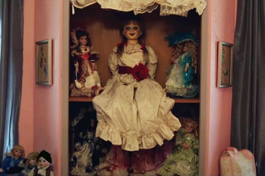 Dolls sit on a pink shelf in Annabelle (2014).