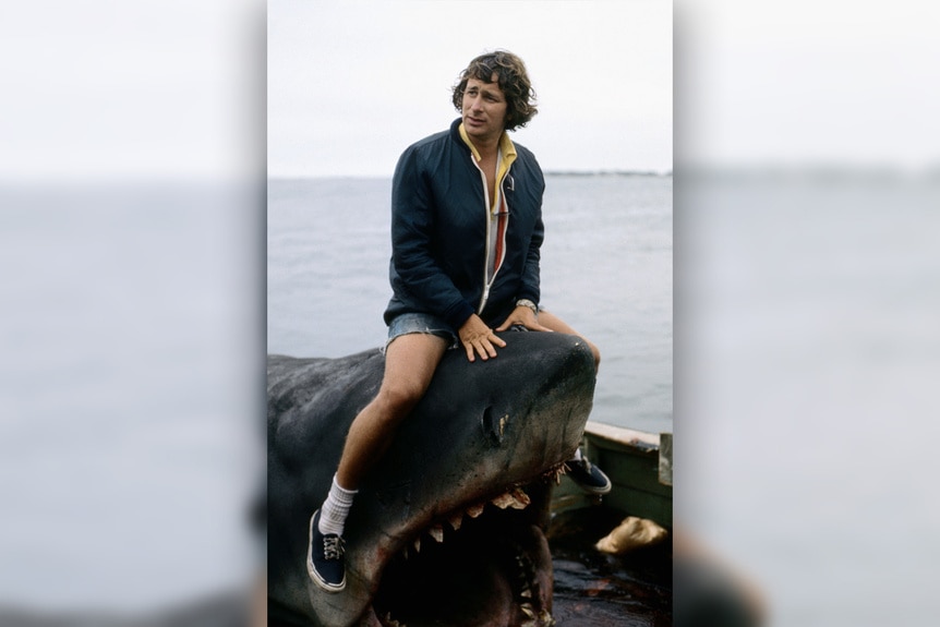 Steven Spielberg rests on a shark.