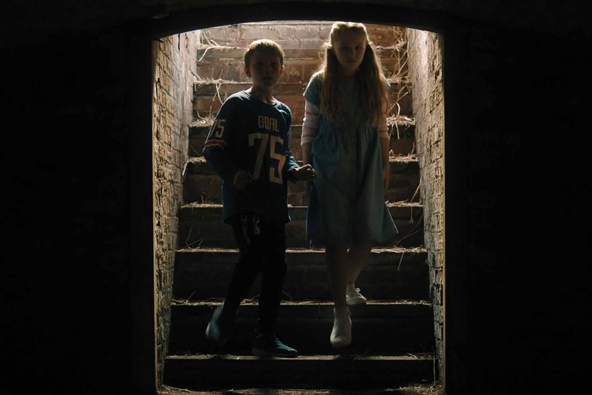 Ant (Dan Hough) and Agnes Dalton (Alix West Lefler) walk down basement steps in Speak No Evil (2024).