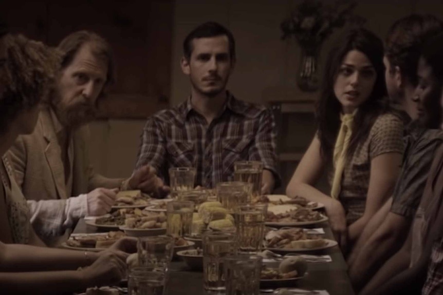 Aaron Smith (Aaron Moorhead) sits at a dinner table on The Endless (2017).