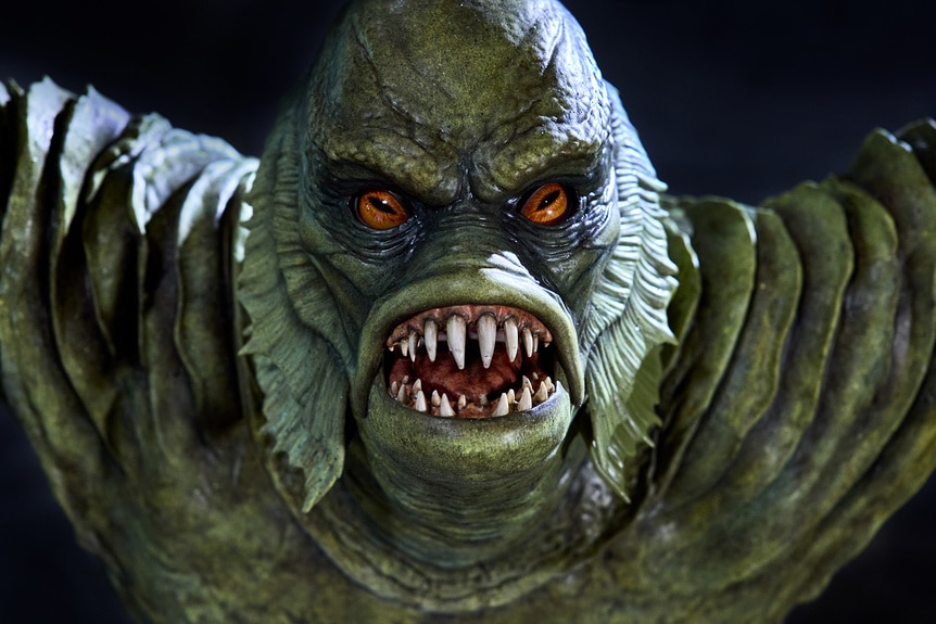 An Animatronic statue of The Creature From The Black Lagoon with red eyes and showing his teeth