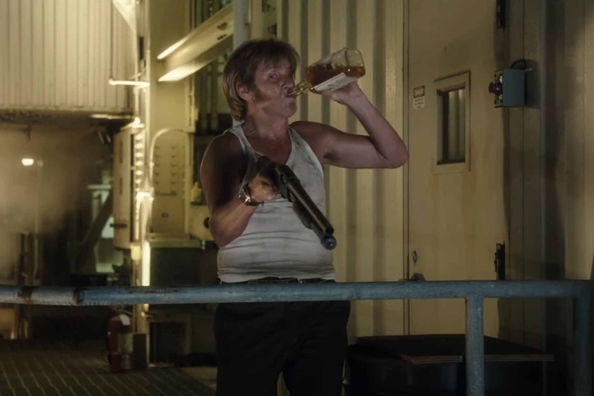 Rick Wilson (Denis Leary) chugs a beer and shoots a shotgun in Freaks of Nature (2015).