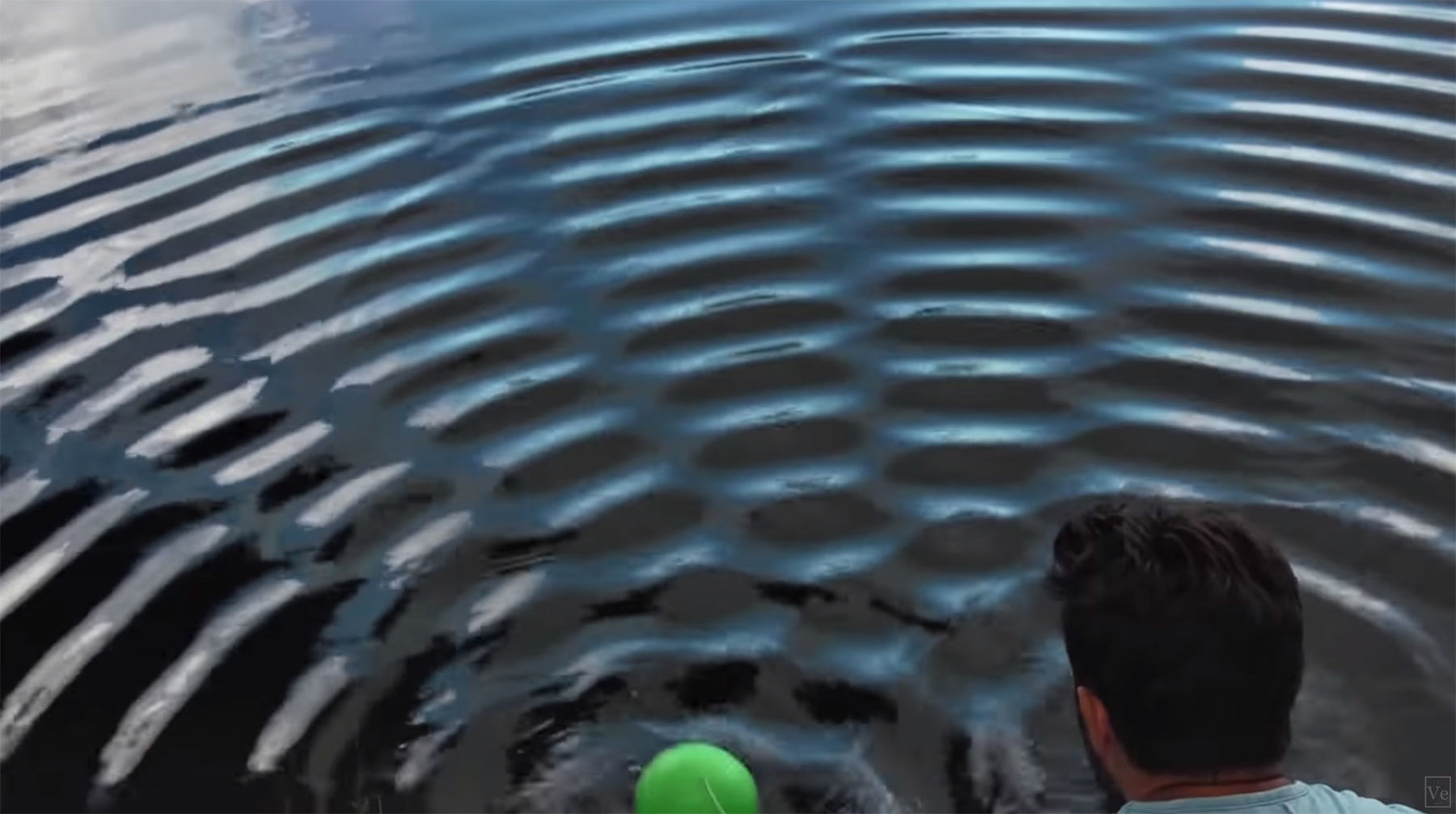 A wave interference pattern created by oscillating two balls in water. Each ball sends out a circular wave, and where they meet the wave crests and trough interact. Credit: Derek Muller, Veritasium (from the video). 